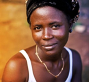 A young African American woman with soft smile wearing a white tank top, a gold necklace.