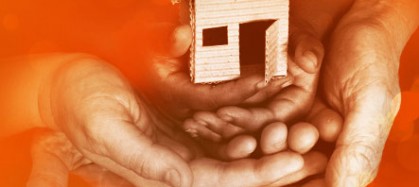 The hands of three people, male, female and child holding a miniature house.