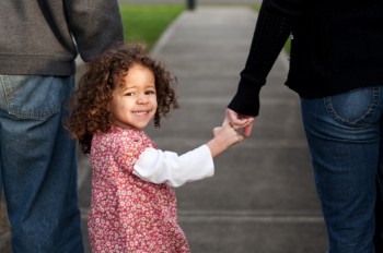 Family of three holding hands with little girl in middle