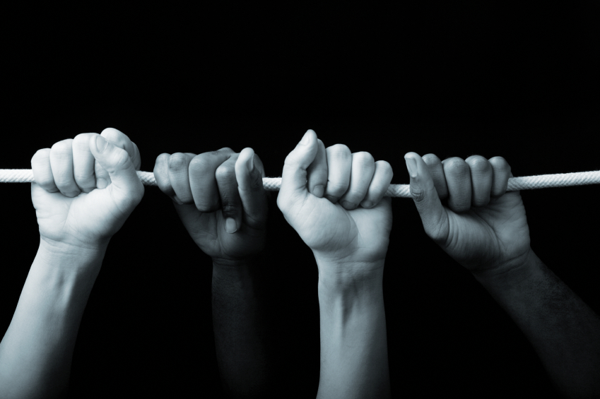 The hands of two people grasping a rope