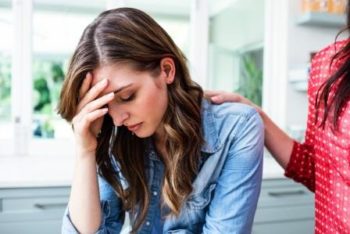 Young woman sad and another woman's hand on her shoulder