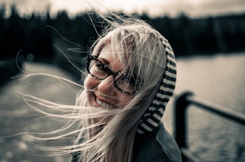 Woman with glasses smiling and hair blowing in the wind