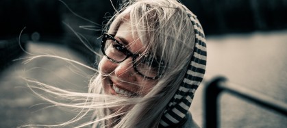 Woman with glasses smiling and hair blowing in the wind
