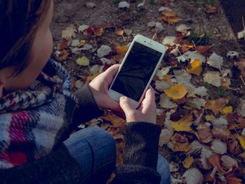 Woman scrolling cellphone and sitting outside