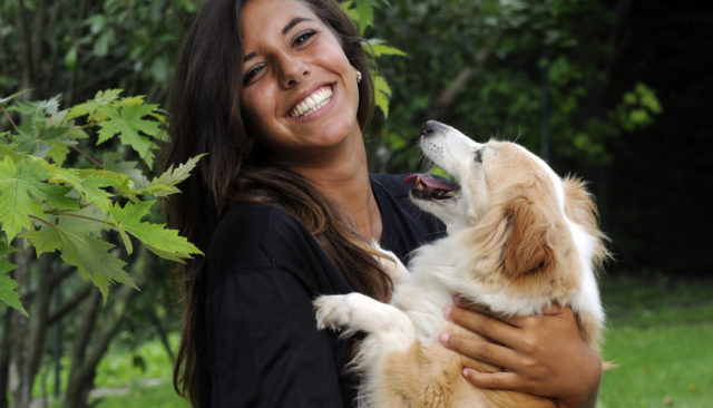 Woman holding her dog and smiling