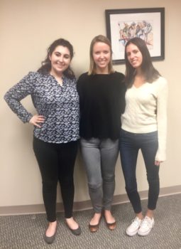 Three young female interns smiling and standing side by side