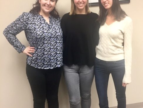 Three young female interns smiling and standing side by side