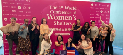 NNEDV staff poses in front of the the Fourth Global Conference of Women's Shelters sign.